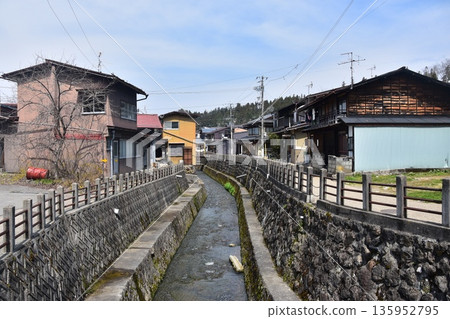 Old townscape of Takayama City, Gifu Prefecture, Japan. Old houses exuding a sense of history. Morning scene during the Takayama Spring Festival. A stream running through the city. Old townscape of Takayama City, Gifu Prefecture, Japan. Old houses exuding a sense of history. Morning scene during the Takayama Spring Festival. A stream running through the city. 135952795