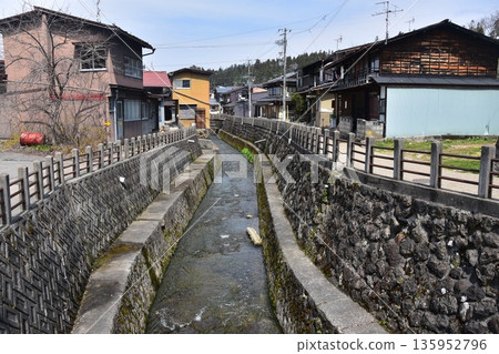Old townscape of Takayama City, Gifu Prefecture, Japan. Old houses exuding a sense of history. Morning scene during the Takayama Spring Festival. A stream running through the city. Old townscape of Takayama City, Gifu Prefecture, Japan. Old houses exuding a sense of history. Morning scene during the Takayama Spring Festival. A stream running through the city. 135952796