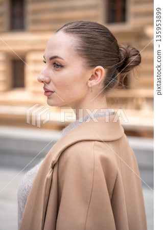 Portrait of young beautiful woman wearing coat walking in the city centre of Prague, Europe Portrait of young beautiful woman wearing coat walking in the city centre of Prague, Europe 135953899