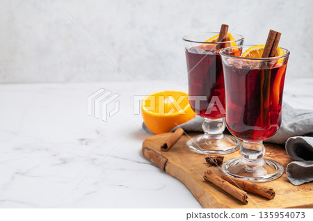 Two glasses of mulled wine, orange, cinnamon, and star anise on a wooden board Two glasses of mulled wine, orange, cinnamon, and star anise on a wooden board 135954073
