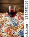 Red wine glass on a pile of euro banknotes during a wine sale event 135955119