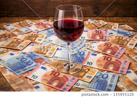 Red wine glass on a pile of euro banknotes during a wine sale event 135955120