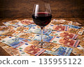 Red wine glass on a pile of euro banknotes during a wine sale event 135955122