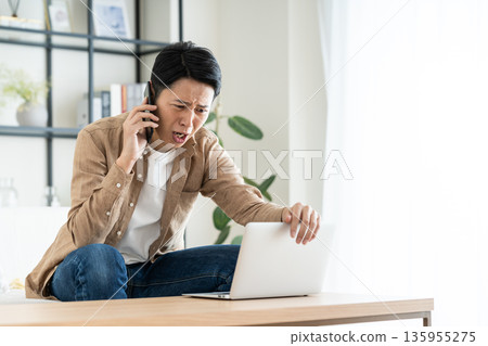 Middle man using a computer in the living room Middle man using a computer in the living room 135955275
