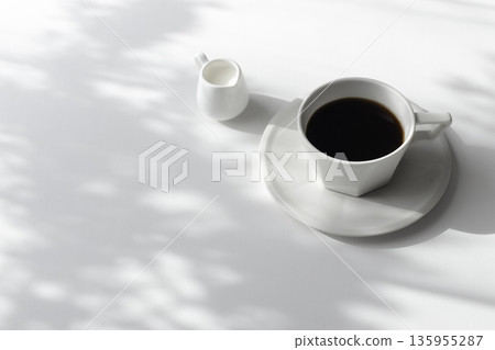 Coffee and milk pitcher on a white background, shadows from sunlight filtering through the trees, and white space Coffee and milk pitcher on a white background, shadows from sunlight filtering through the trees, and white space 135955287