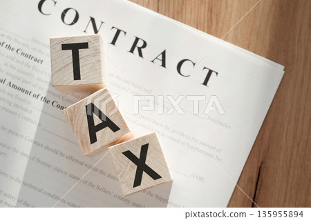 Word TAX on wooden cubes on contract documents background. 135955894
