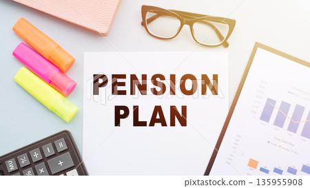 The text PENSION PLAN on office desk with calculator, markers, glasses and financial charts. 135955908