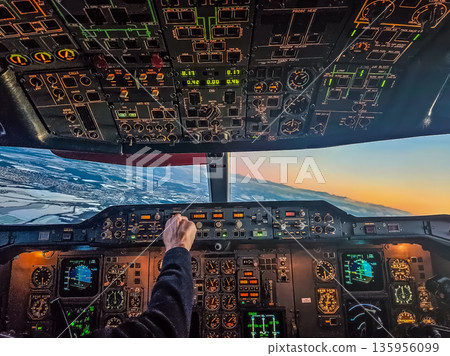 Pilots view from the cockpit of a classic jet flying at sunset over a winter landscape. 135956099