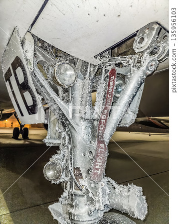 Frozen Remove Before Flight tag on an icy aircraft landing gear at a winter airport. 135956103