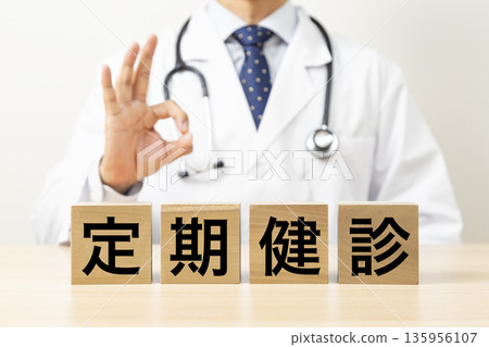 A block with "Regular Health Checkup" written on it and a doctor making an OK sign A block with "Regular Health Checkup" written on it and a doctor making an OK sign 135956107