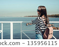 Beautiful young woman with a backpack on a background of the sea. Outdoors, lifestyle 135956115