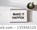 A white spiral notebook with the words Make It Happen written in 135956120