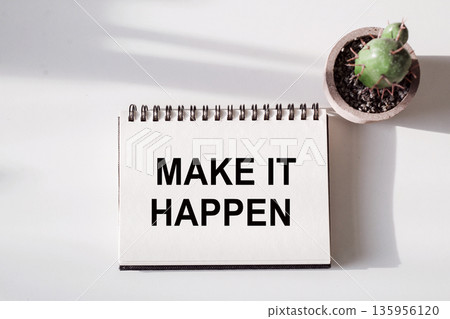 A white spiral notebook with the words Make It Happen written in 135956120
