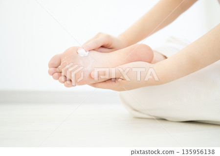 Woman applying cream for treatment peeling and cracked foot. Causes of peeling foot included fungal infection (athlete's foot), dermatitis (eczema), sunburn, dry skin, dehydration or sweaty feet. 135956138