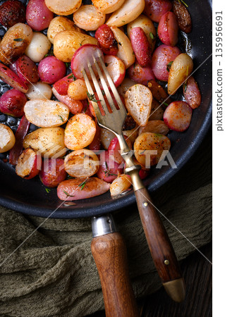 Baked radishes with herbs in black skillet with vintage cutlery Baked radishes with herbs in black skillet with vintage cutlery 135956691