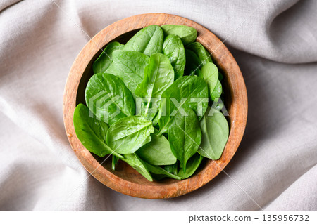 Flat lay of bright green spinach arranged in wooden bowl Flat lay of bright green spinach arranged in wooden bowl 135956732