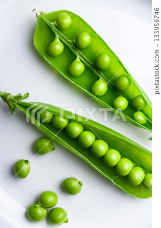 Fresh green peas in open pods on white plate 135956746