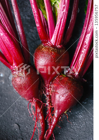 Fresh raw beetroot with stems on dark background Fresh raw beetroot with stems on dark background 135956757