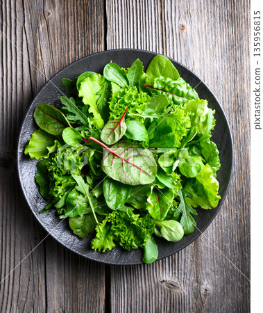 Green salad leaves with curly lettuce arranged on black plate Green salad leaves with curly lettuce arranged on black plate 135956815