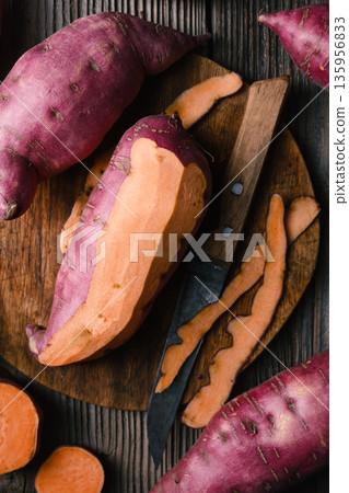 Raw sweet potato with cut pieces on dark wooden surface Raw sweet potato with cut pieces on dark wooden surface 135956833
