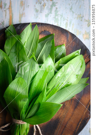 Wild garlic bundle placed on wooden board close up 135956875