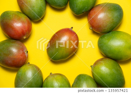 Composition of fresh mangoes on yellow surface. Composition of fresh mangoes on yellow surface. 135957421