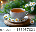 Luxury tea cup styled with fresh white chamomile flowers. Premium non-alcoholic drink presentation, wellness lifestyle, calm energy, natural healthy beverage, herbal drinks, cozy morning atmosphere. 135957821