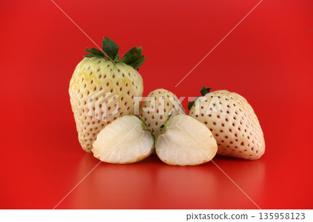 Unique white pineberries with red seeds displayed on a vibrant red background Unique white pineberries with red seeds displayed on a vibrant red background 135958123