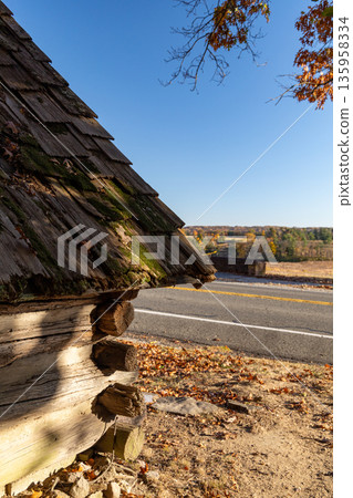 A log cabin with moss growing on it sits on a dirt road A log cabin with moss growing on it sits on a dirt road 135958334