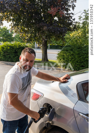 A man is filling up his car with gas 135958342