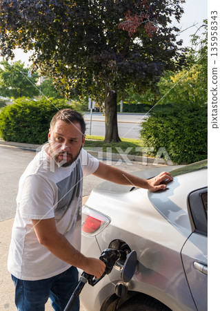 A man is filling up his car with gas 135958343
