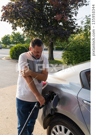 A man is filling up his car with gas 135958344