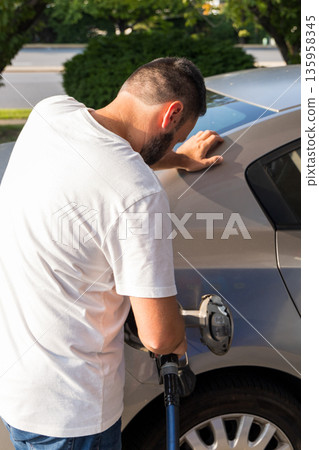 A man is filling up his car with gas 135958345