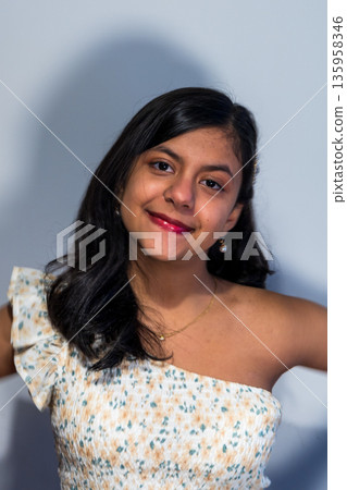 A young woman is wearing a white and yellow floral dress and smiling 135958346