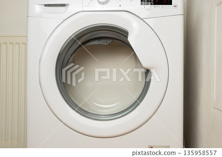 Front view of laundry washer in process of cleaning clothes Front view of laundry washer in process of cleaning clothes 135958557