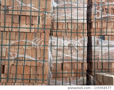 Stacked bricks in construction site tied with plastic wrap, creating textured background Stacked bricks in construction site tied with plastic wrap, creating textured background 135958577