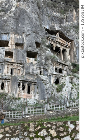 Ancient rock-cut tombs carved into hillside, historical site with rugged stone, background potential 135958594