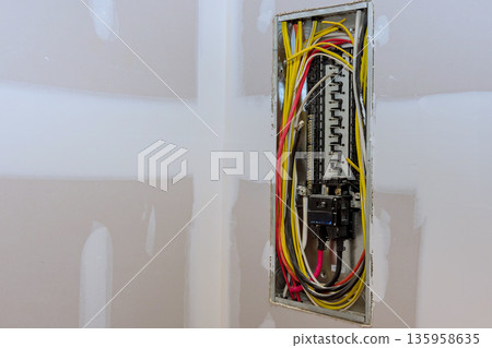 Wires link to circuit breakers in an electrical panel at construction site prior to installation inspection. 135958635