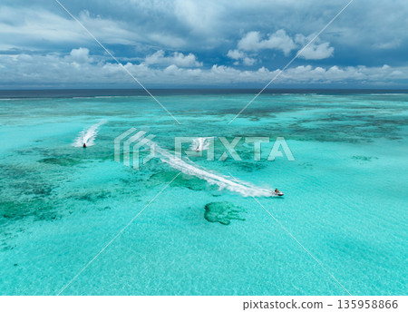 Aerial view of jet skis over shallow turquoise sea with reef 135958866