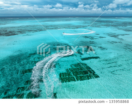 Aerial view of jet skis over shallow turquoise sea with reef 135958868