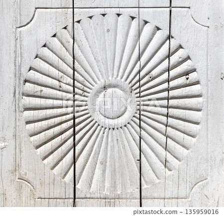 A detailed sunburst carving etched into a whitewashed wooden panel A detailed sunburst carving etched into a whitewashed wooden panel 135959016