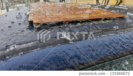 Rusty metal sheet placed on icy car roof with frozen droplets and sheen under winter light, showing corroded surface texture against slick frozen background. Rusty metal sheet placed on icy car roof with frozen droplets and sheen under winter light, showing corroded surface texture against slick frozen background. 135960672