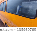 Yellow van covered in thick frost on side windows and body, showing icy buildup and lack of visibility through frozen panels during cold snowy conditions. 135960765