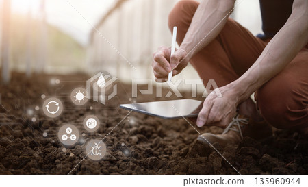 Farmer checks soil quality by hand using digital data icons to analyze nutrients pH moisture with tablet 135960944
