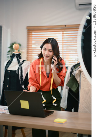 Fashion blogger concept, Young Asian women selling clothes and talking her smartphone with customer Fashion blogger concept, Young Asian women selling clothes and talking her smartphone with customer 135960956