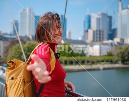 Tourist woman explores modern Frankfurt, walking through vibrant streets with contemporary architecture, skyscrapers, and urban spaces, enjoying lively atmosphere of modern side. Tourist woman explores modern Frankfurt, walking through vibrant streets with contemporary architecture, skyscrapers, and urban spaces, enjoying lively atmosphere of modern side. 135961088