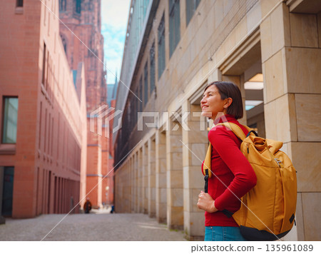 Tourist woman strolls through old town of Frankfurt, exploring its historic streets, beautiful architecture, and cultural landmarks, enjoying vibrant atmosphere of citys past. Tourist woman strolls through old town of Frankfurt, exploring its historic streets, beautiful architecture, and cultural landmarks, enjoying vibrant atmosphere of citys past. 135961089