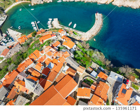 Drone captures stunning top view of Baska towns on Krk Island in Croatia. Blue Adriatic Sea meets rocky coastline and traditional Mediterranean architecture from above. Drone captures stunning top view of Baska towns on Krk Island in Croatia. Blue Adriatic Sea meets rocky coastline and traditional Mediterranean architecture from above. 135961171