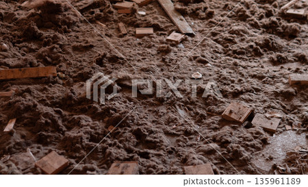 A cluttered room shows a dusty floor covered with pieces of wood and debris. Light from the late afternoon sun highlights the dirt and mess in the area. A cluttered room shows a dusty floor covered with pieces of wood and debris. Light from the late afternoon sun highlights the dirt and mess in the area. 135961189