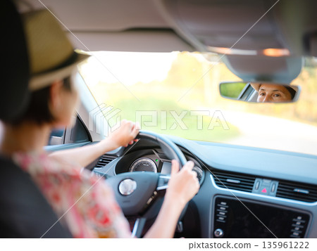 Young woman drives through scenic countryside, hands on wheel, focused on road ahead. Peaceful summer journey through rural landscapes captures freedom and adventure. Croatia, Europe Young woman drives through scenic countryside, hands on wheel, focused on road ahead. Peaceful summer journey through rural landscapes captures freedom and adventure. Croatia, Europe 135961222